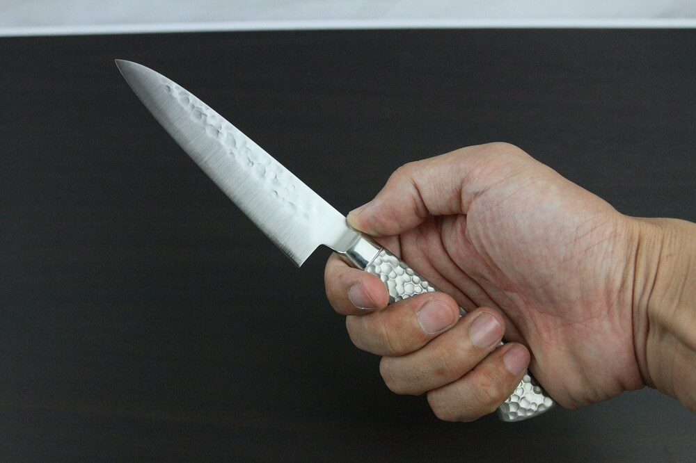 hamfin_petit120_08 Japanese Chef Knife, Hammer Finish Series, Petit knife 120mm, grabbed by a man's hand