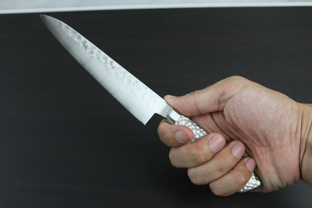 hamfin_petit150_08 Japanese Chef Knife, Hammer Finish Series, Petit knife 150mm, grabbed by a man's hand
