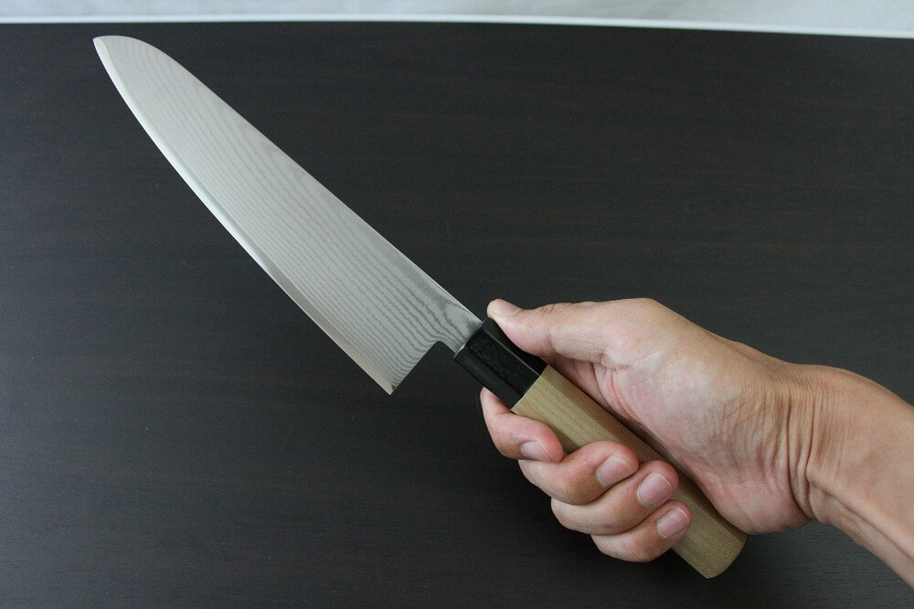 spsantoku_dam8_IMG_6233 Toshu Santoku multi-purpose Japanese chef's knife, damascus blade and octagonal wood handle, grabbed by a man's hand