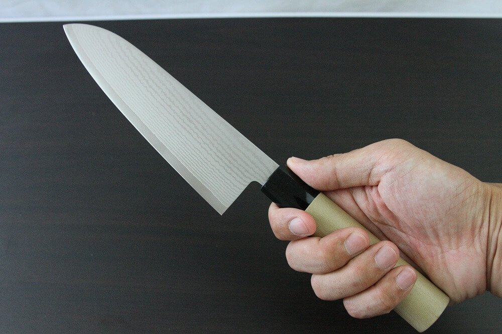 spsantoku_hou_IMG_6236 Toshu Santoku multi-purpose Japanese chef's knife, damascus blade and traditional wood handle, grabbed by a man's hand